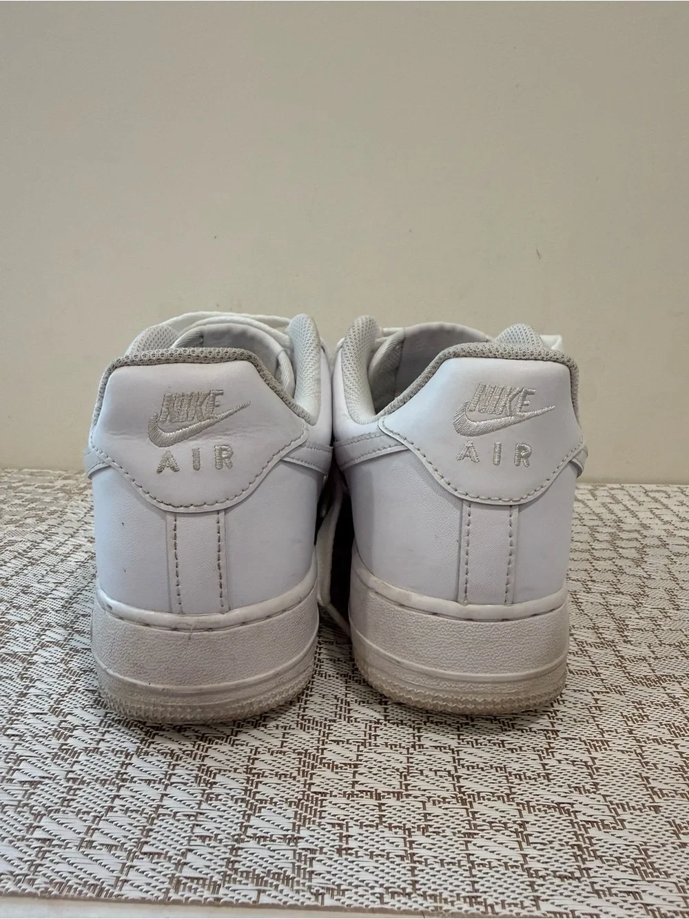 These are iconic Nike Air Force 1 sneakers in an all-white colorway.